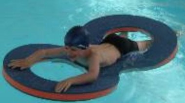 Personne nageant dans une piscine avec un flotteur annulaire gris-bleu et orange, utilisant un dispositif en forme de cercle pour se maintenir.